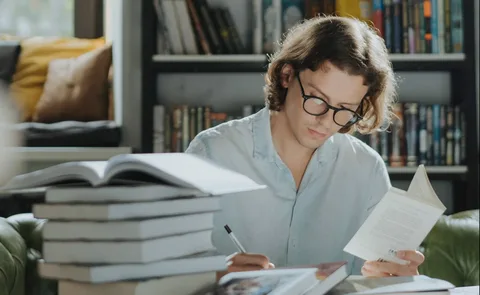 Researcher reading beside a stack of books